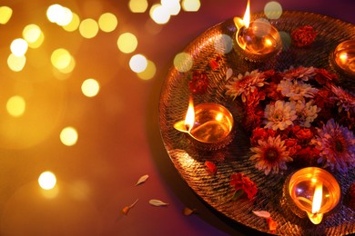 Image of Diwali celebration. Diya lamps and beautiful flowers on color background. Bokeh effect