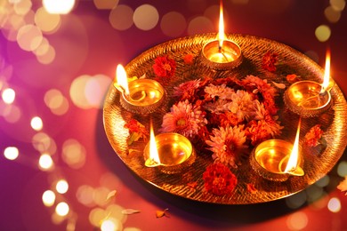 Image of Diwali celebration. Diya lamps and beautiful flowers on color background. Bokeh effect