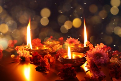 Image of Diwali celebration. Diya lamps and beautiful flowers on dark background. Bokeh effect