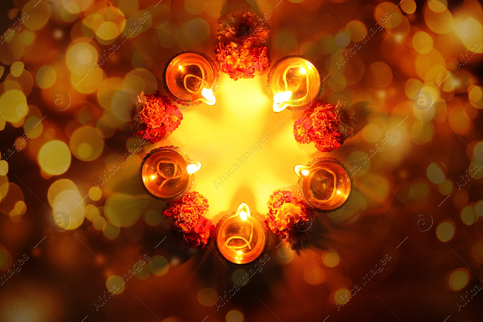 Image of Diwali celebration. Diya lamps and beautiful flowers on background with bokeh effect, top view