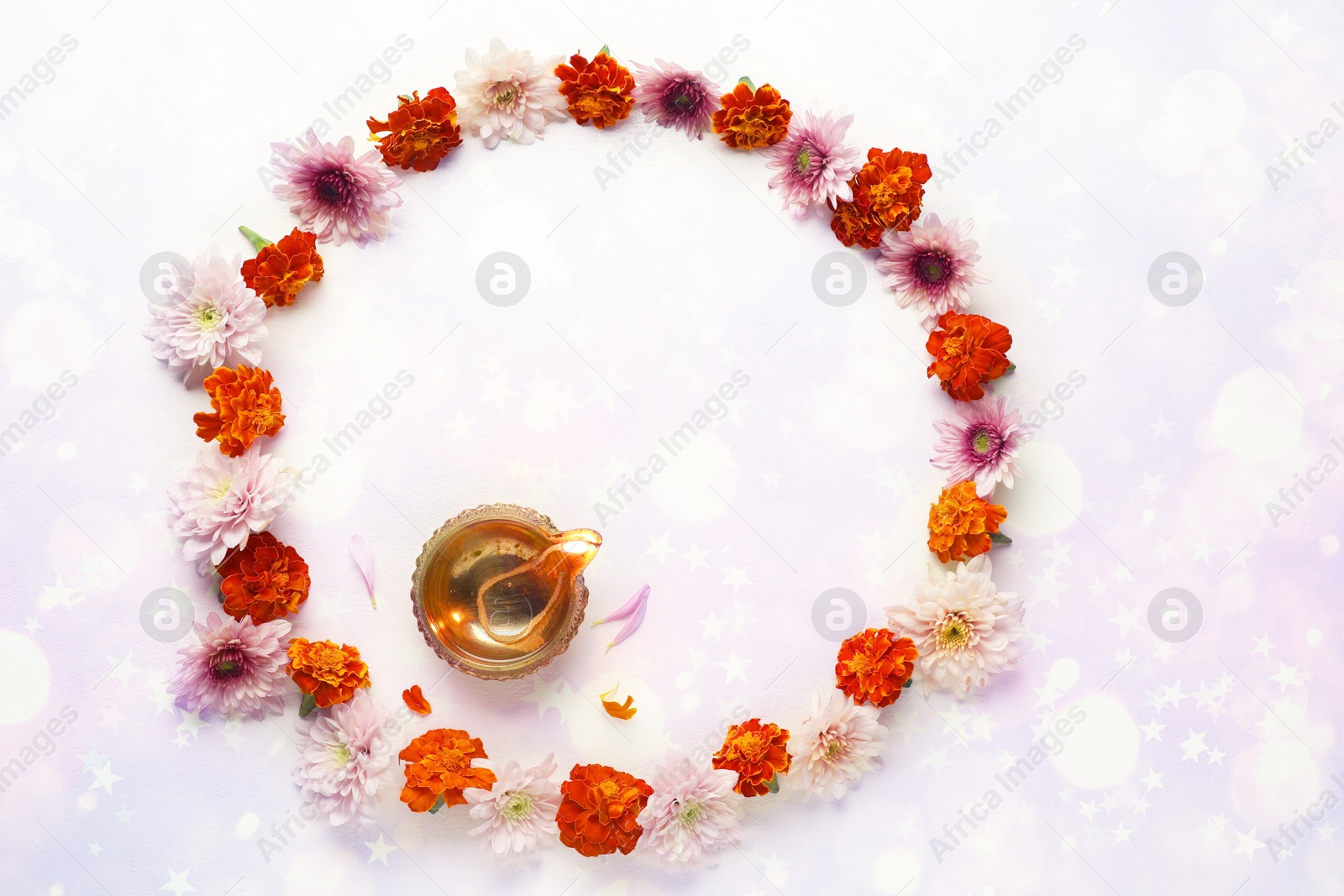 Image of Diwali celebration. Diya lamp and beautiful flowers on light textured surface, flat lay. Space for text. Bokeh effect