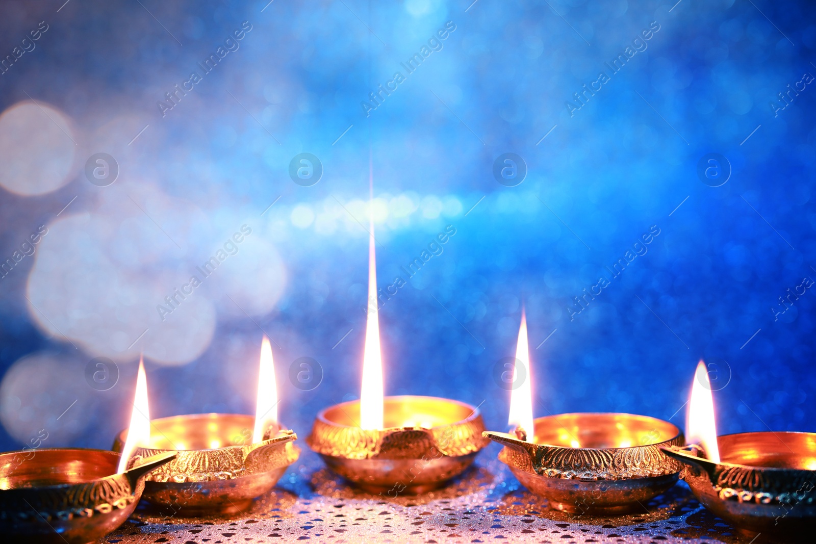 Image of Diwali celebration. Diya lamps on color background. Space for text. Bokeh effect