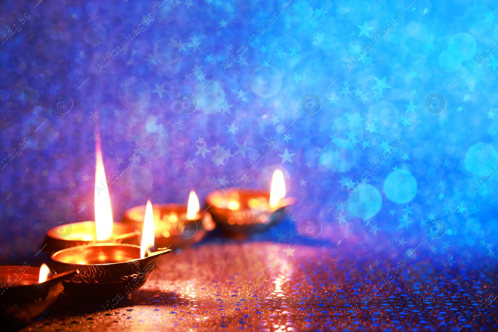 Image of Diwali celebration. Diya lamps on color background. Space for text. Bokeh effect