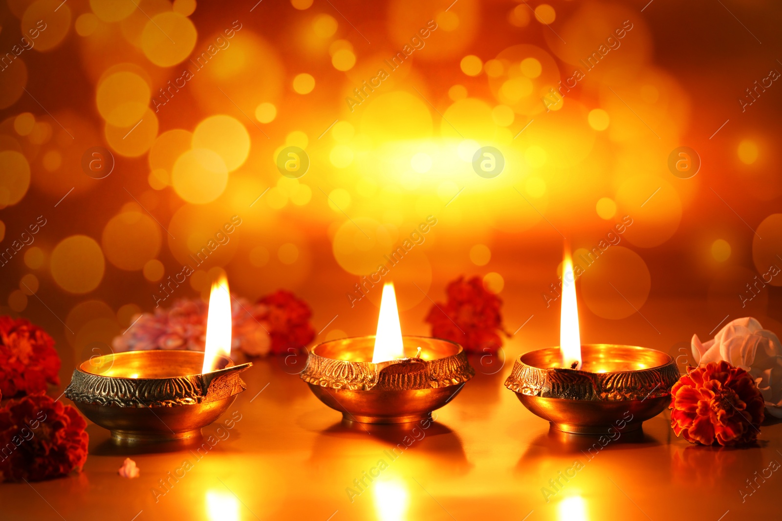 Image of Diwali celebration. Diya lamps and beautiful flowers on golden background. Bokeh effect