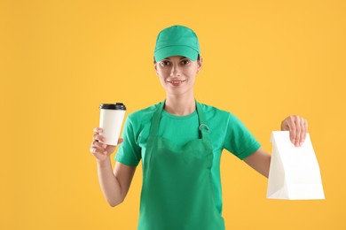 Photo of Fast-food worker with paper bag and cup on orange background