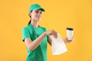 Fast-food worker with paper bag and cup on orange background