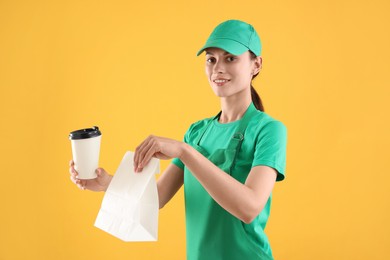 Photo of Fast-food worker with paper bag and cup on orange background