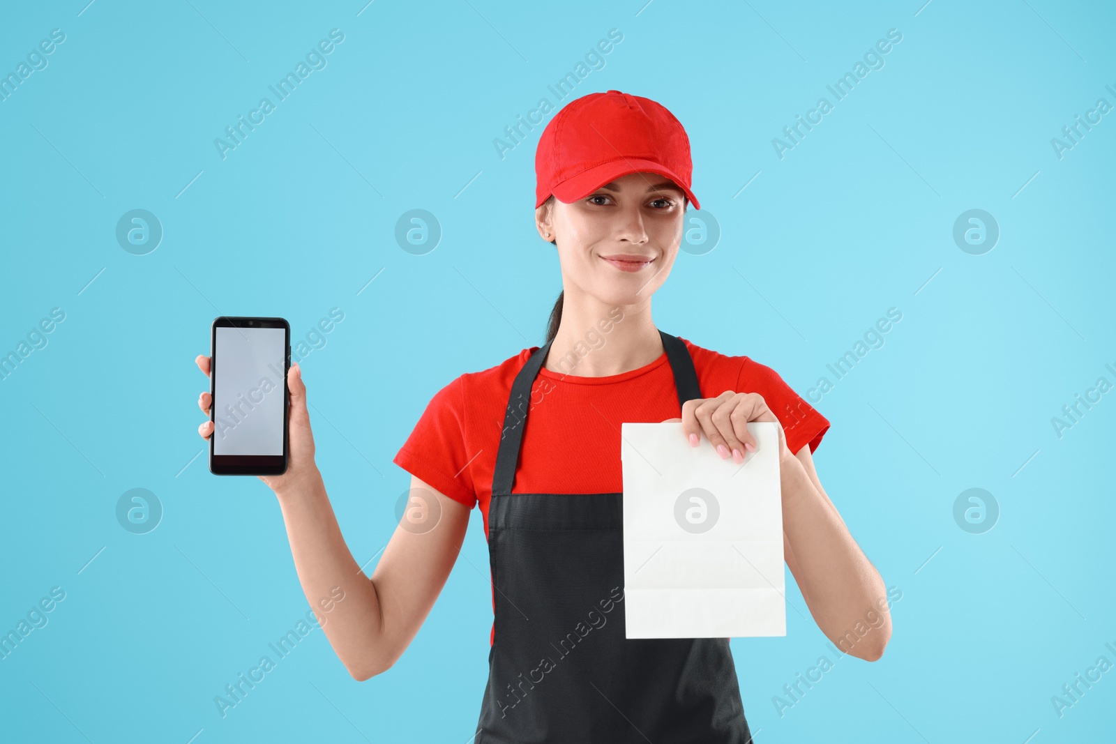 Photo of Fast-food worker with paper bag and smartphone on light blue background