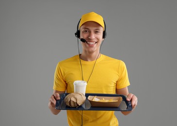 Photo of Fast-food worker holding tray with order on gray background