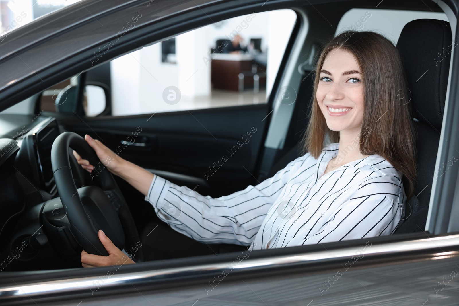 Photo of Happy young woman inside new car in salon