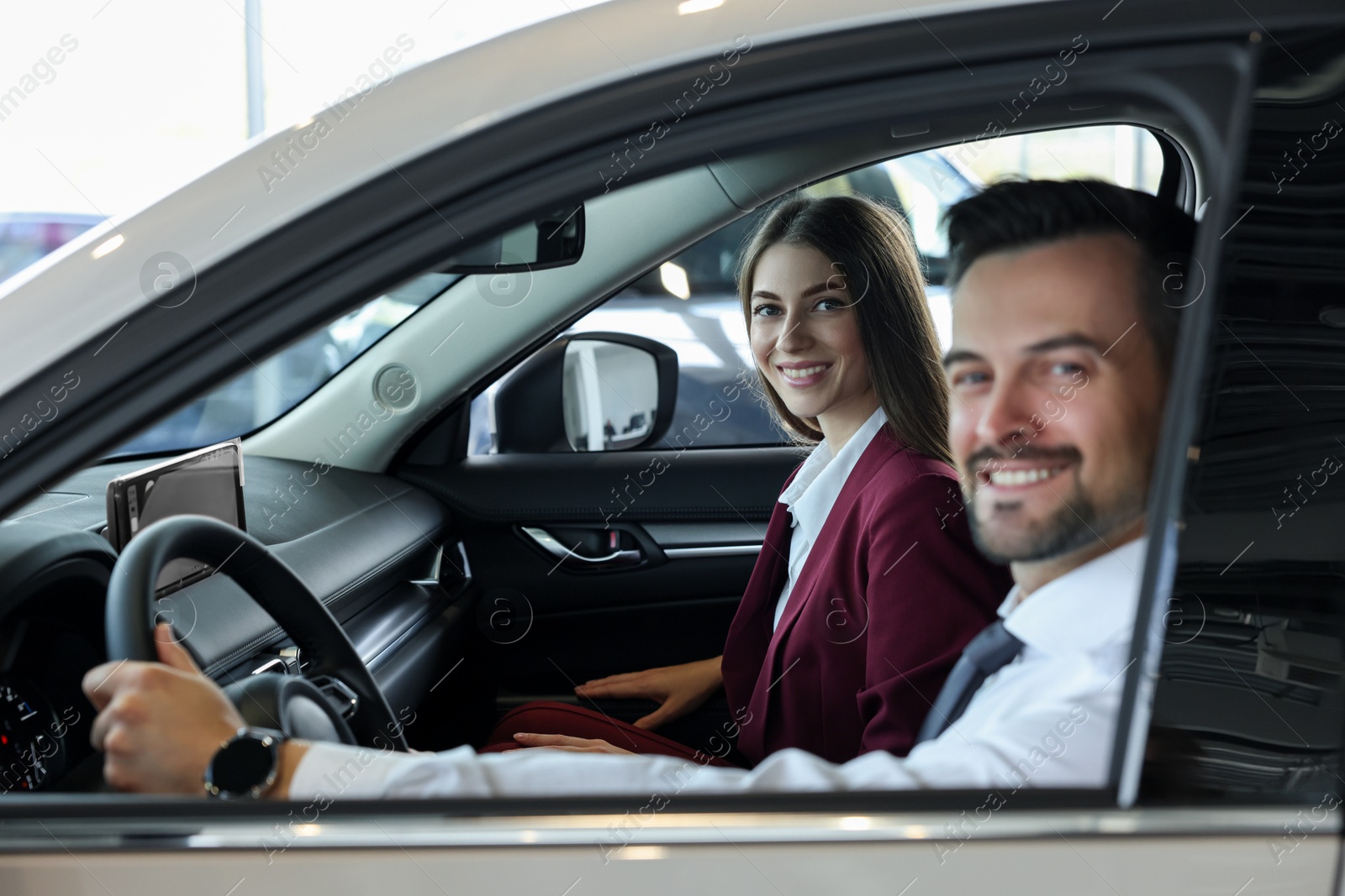 Photo of Happy saleswoman and client inside new car in salon