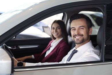 Happy saleswoman and client inside new car in salon