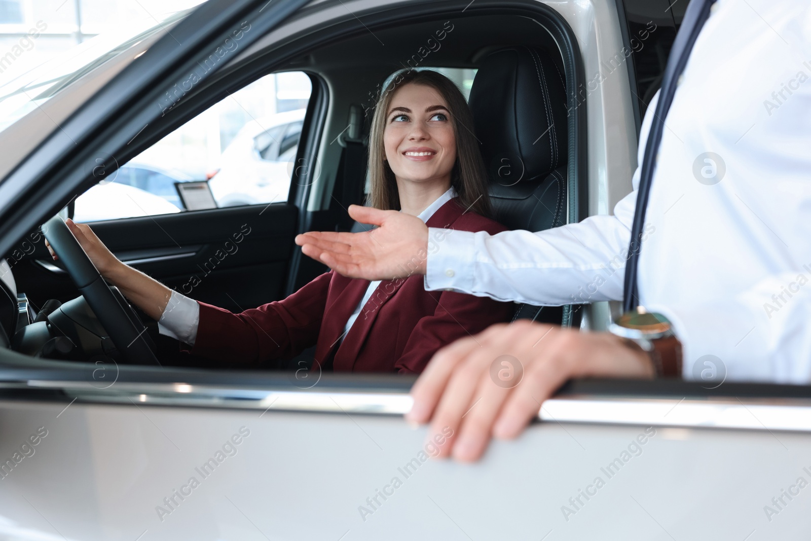 Photo of Happy salesman showing car to client in salon