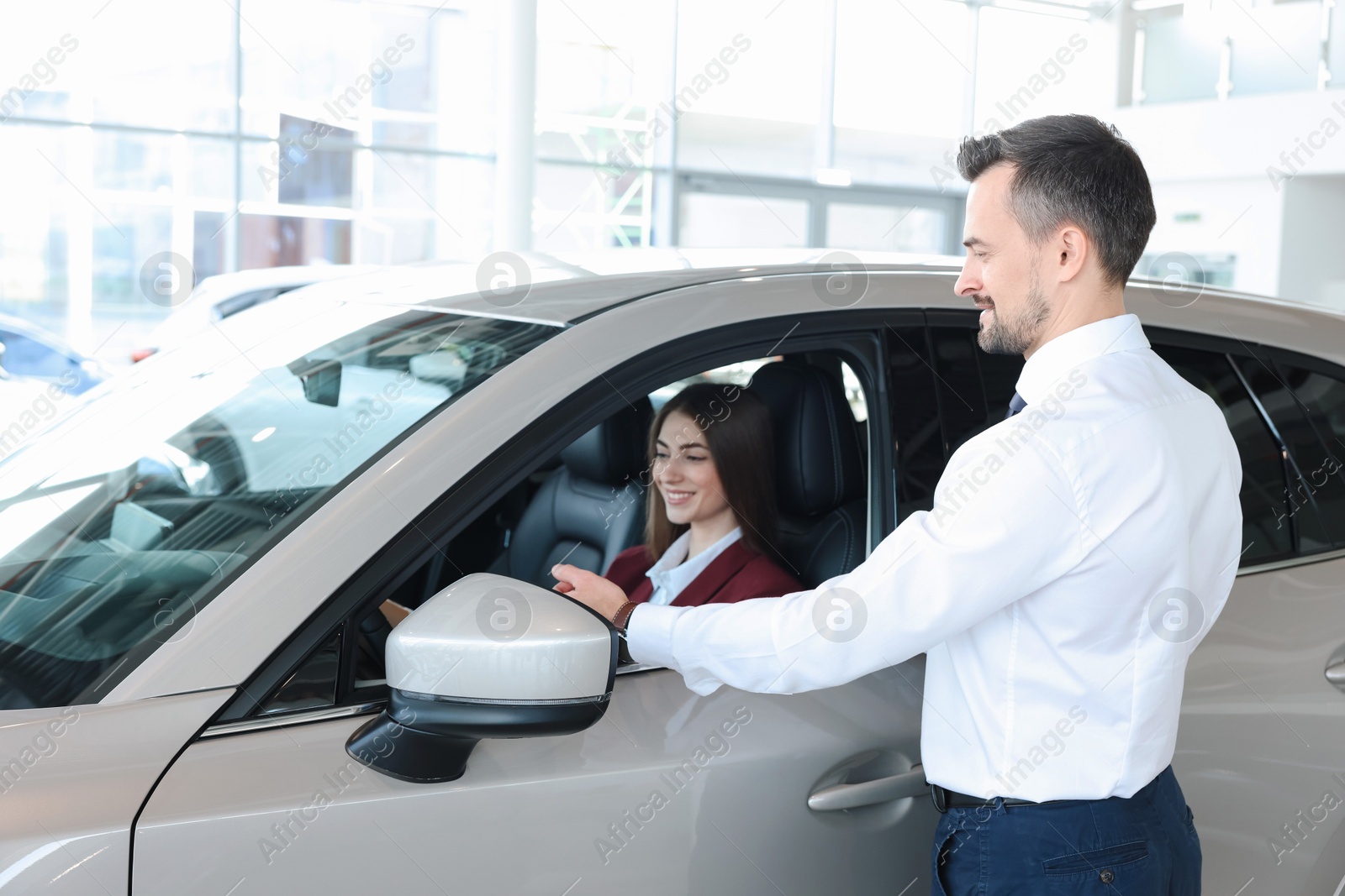 Photo of Happy salesman showing car to client in salon