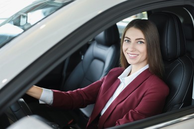 Photo of Young woman inside new car in salon