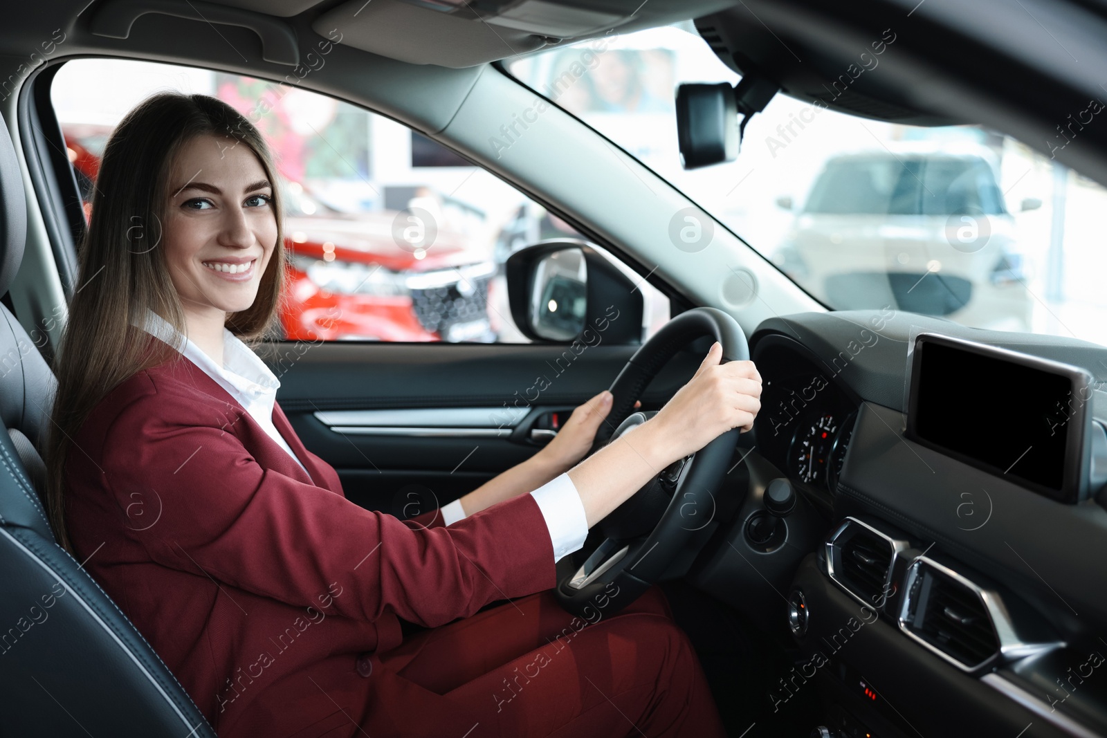 Photo of Young woman inside new car in salon