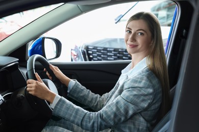 Photo of Young woman inside new car in salon