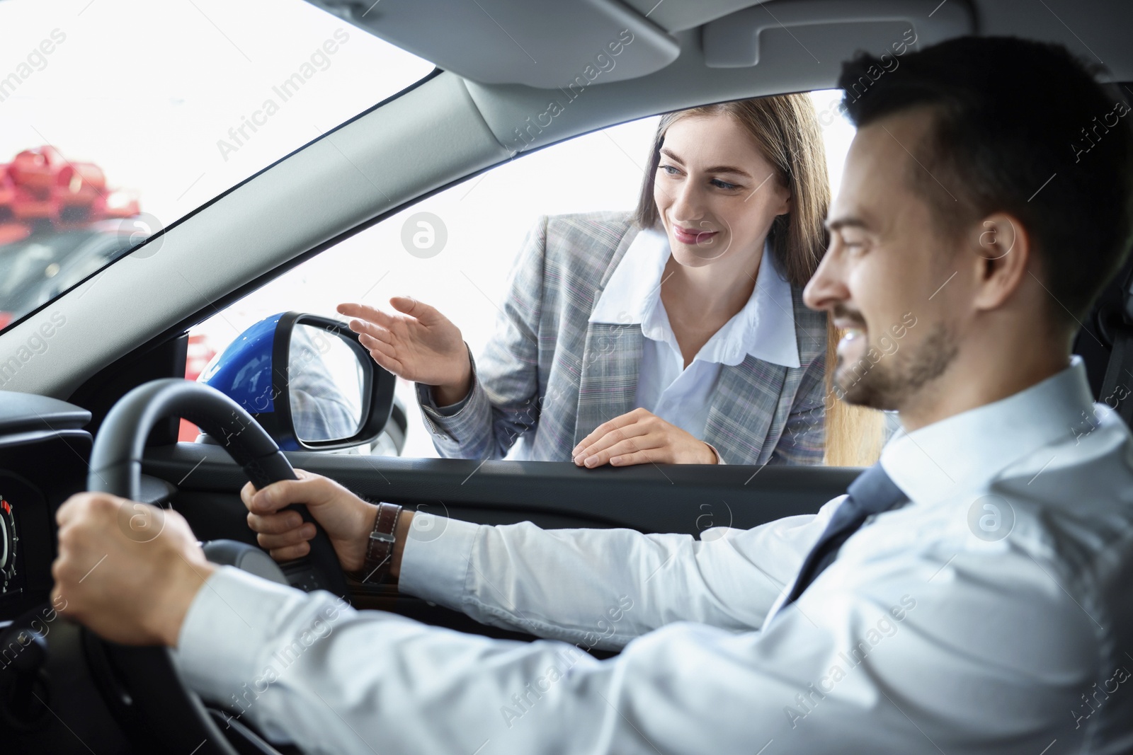 Photo of Saleswoman showing car to client in salon