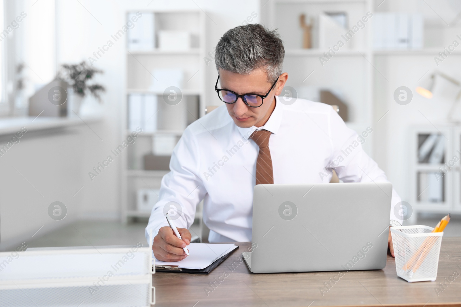 Photo of Middle aged man working at table in office