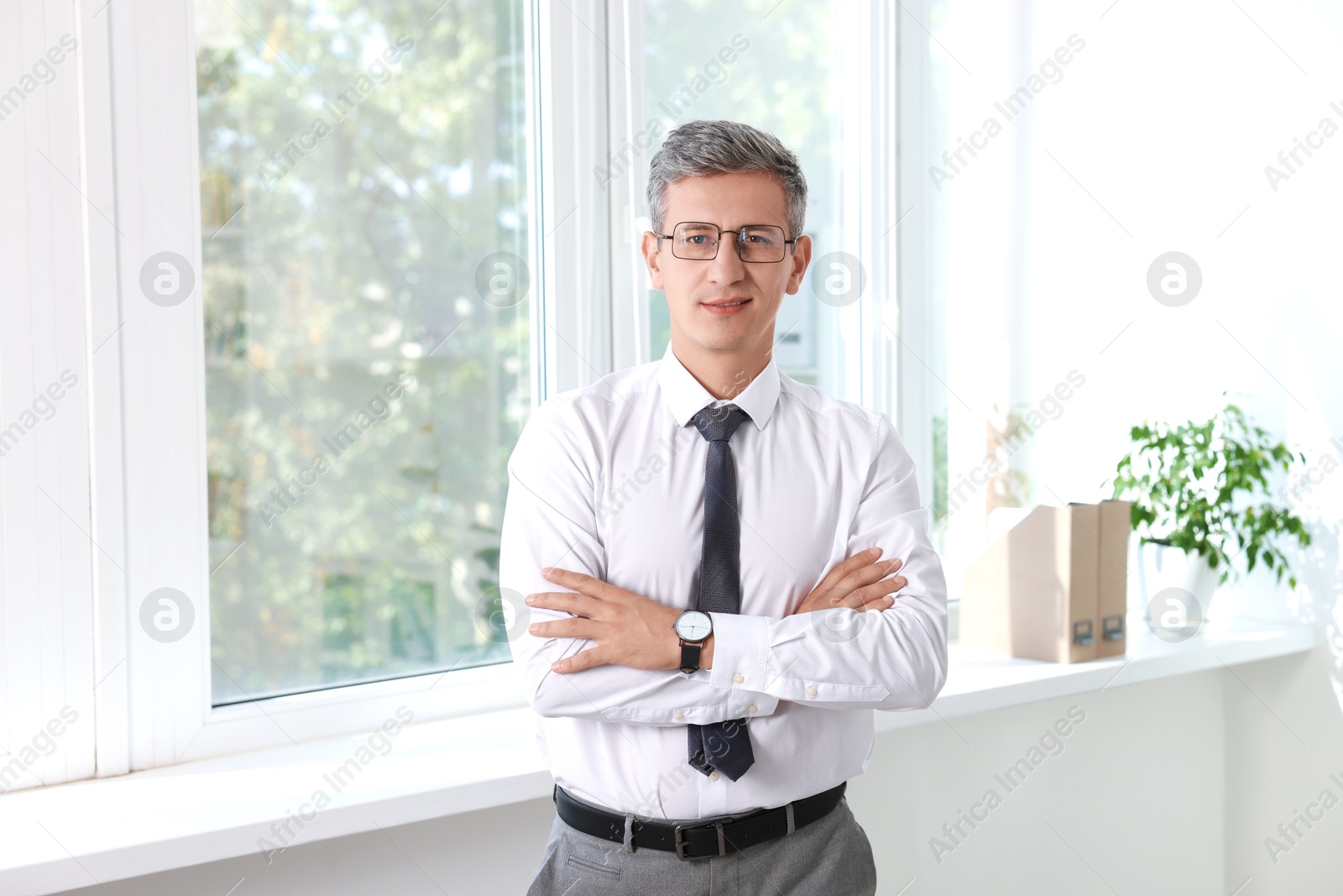 Photo of Portrait of middle aged man with crossed arms in office