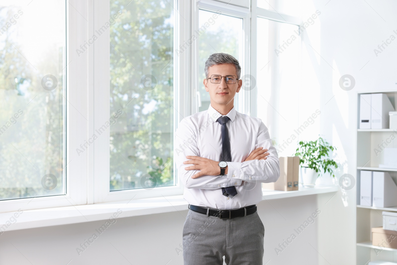 Photo of Portrait of middle aged man with crossed arms in office. Space for text