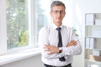 Photo of Portrait of middle aged man with crossed arms in office. Space for text