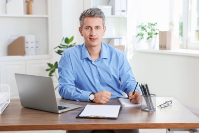 Photo of Portrait of middle aged man at table in office