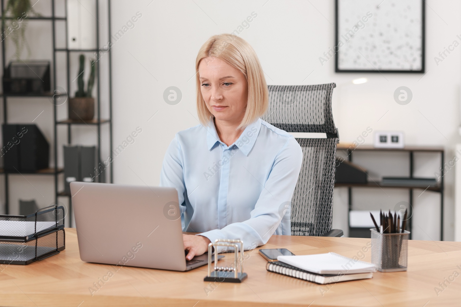 Photo of Middle aged woman working with laptop at table in office