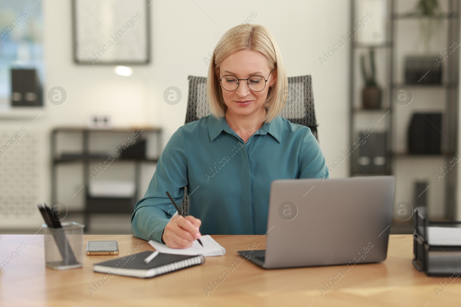 Photo of Middle aged woman working at table in office