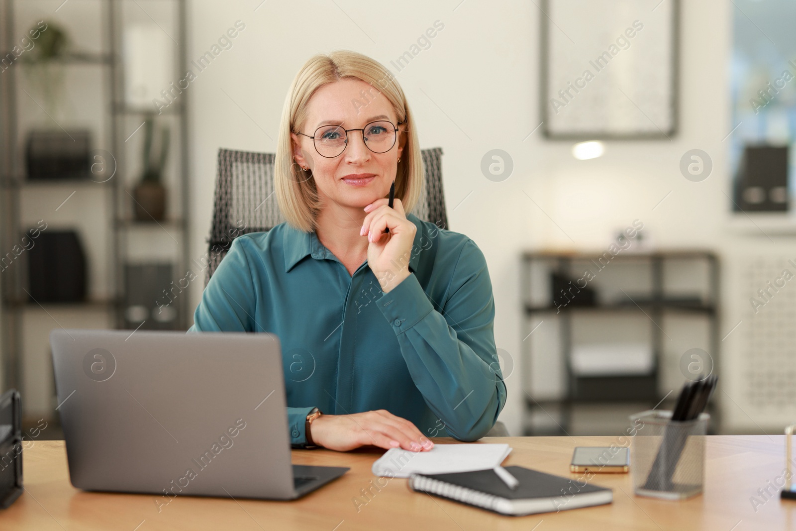 Photo of Portrait of middle aged woman at table in office