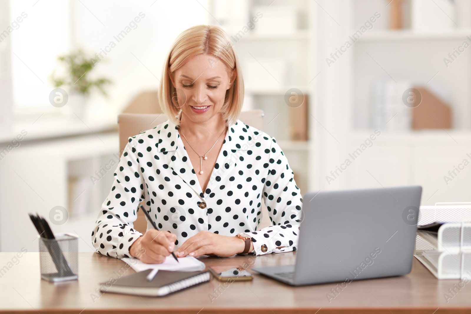 Photo of Smiling middle aged woman working at table in office