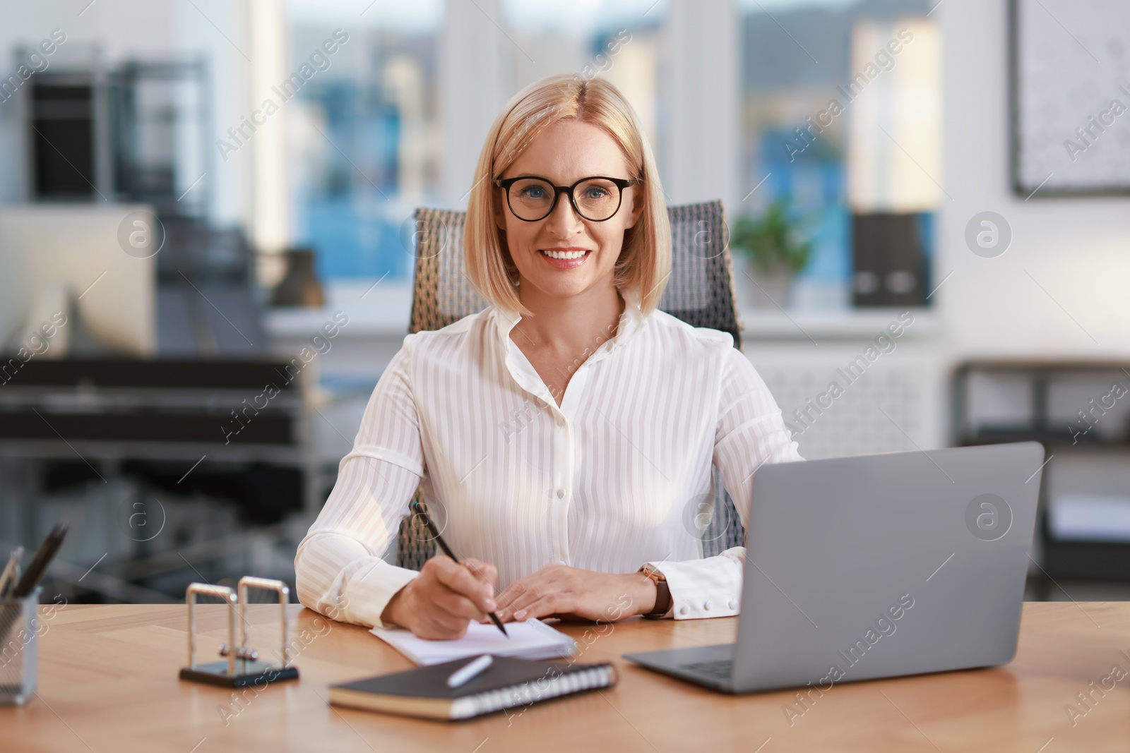 Photo of Portrait of smiling middle aged woman at table in office