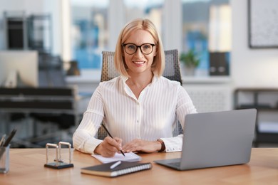 Portrait of smiling middle aged woman at table in office