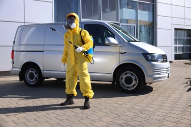 Photo of Pest control worker with spray tank outdoors