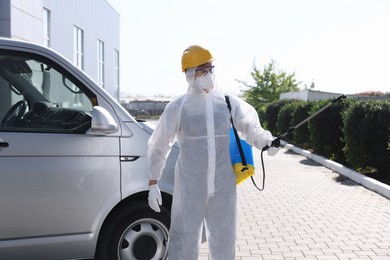 Photo of Pest control worker with spray tank outdoors