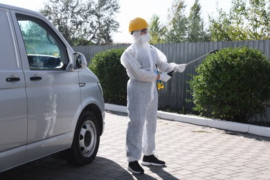 Photo of Pest control worker with spray tank outdoors