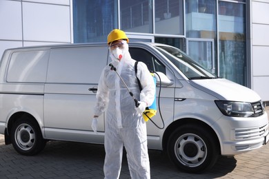 Photo of Pest control worker with spray tank outdoors