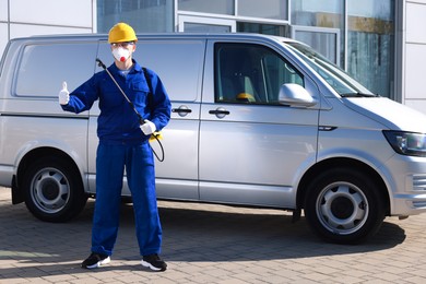 Pest control worker with spray tank showing thumbs up outdoors