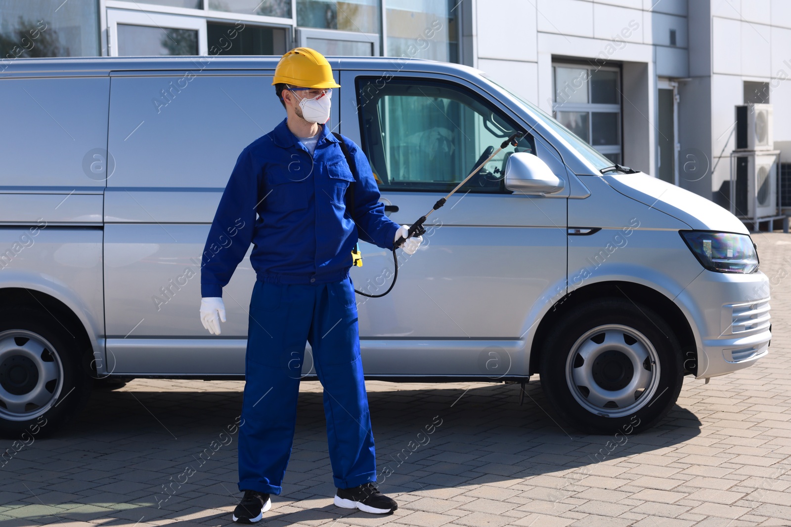 Photo of Pest control worker with spray tank outdoors