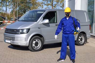 Photo of Pest control worker with spray tank outdoors