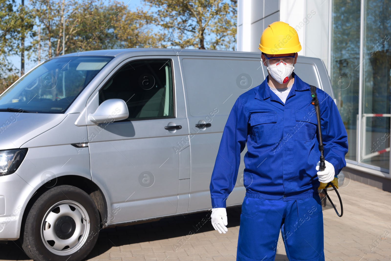 Photo of Pest control worker with spray tank outdoors