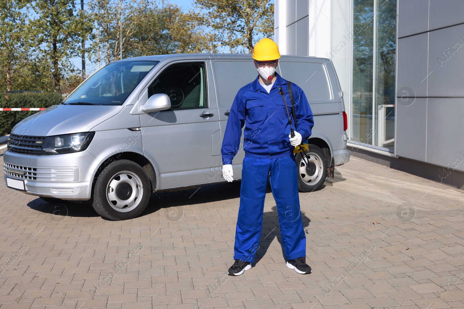 Photo of Pest control worker with spray tank outdoors