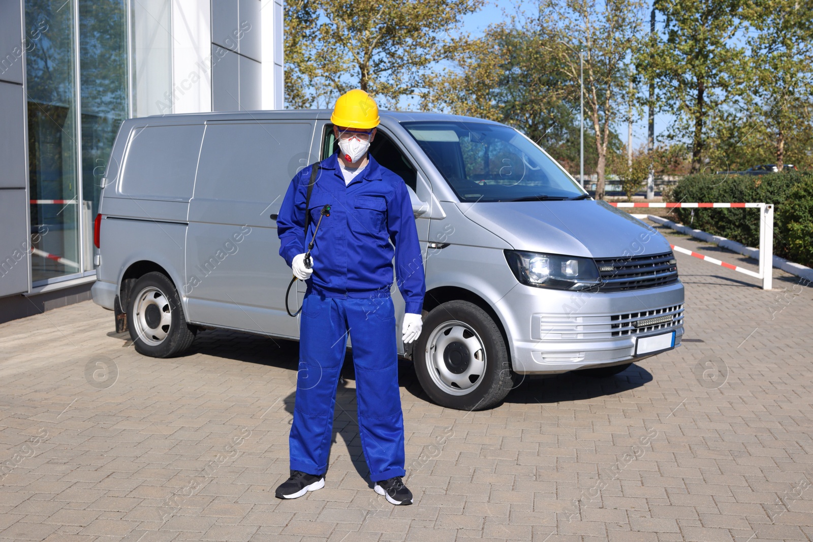 Photo of Pest control worker with spray tank outdoors