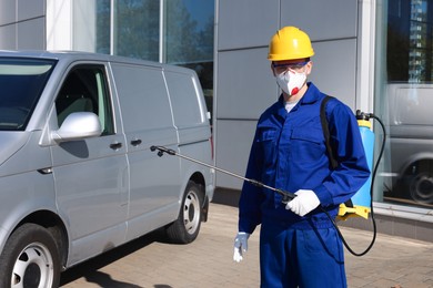 Photo of Pest control worker with spray tank outdoors