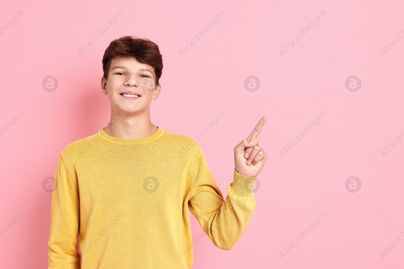 Photo of Portrait of happy teenage boy on pink background, space for text