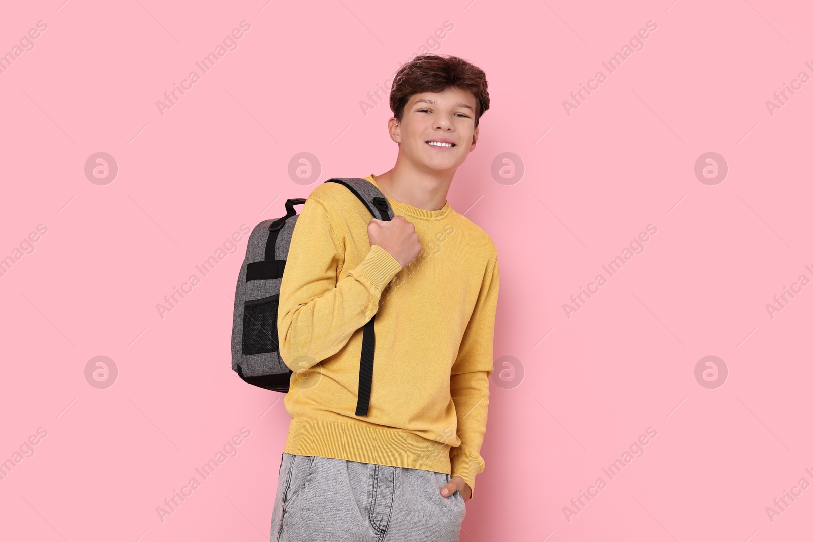 Photo of Happy teenage boy with backpack on pink background