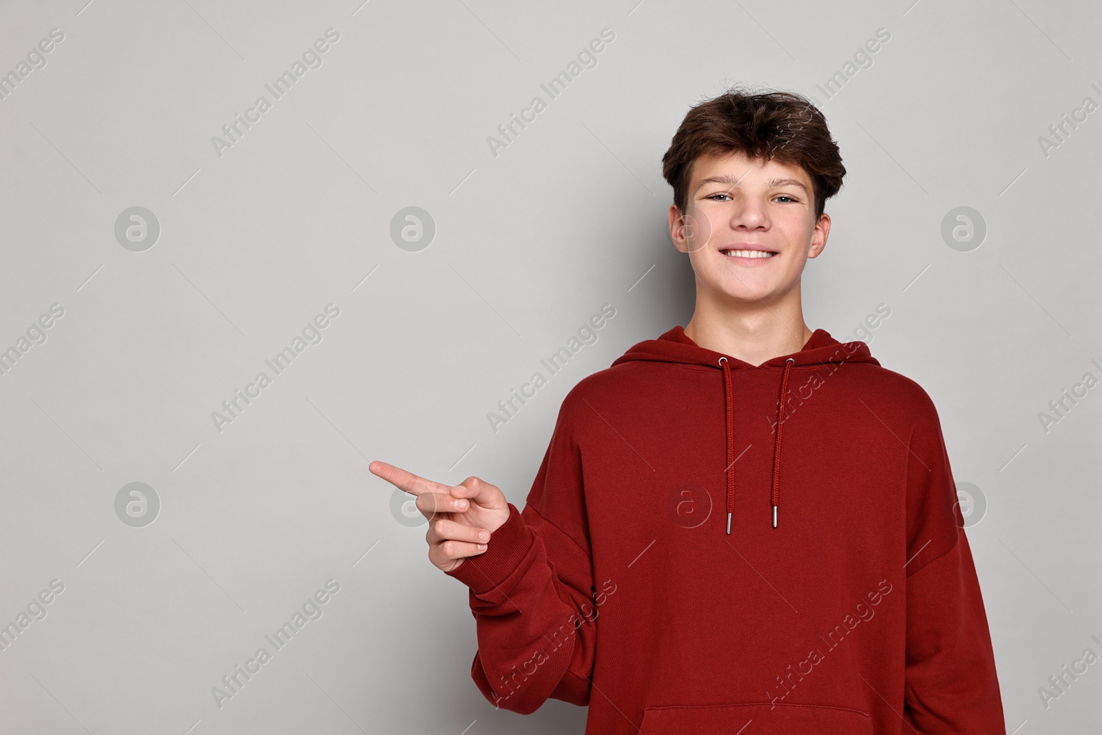 Photo of Portrait of happy teenage boy on light grey background, space for text