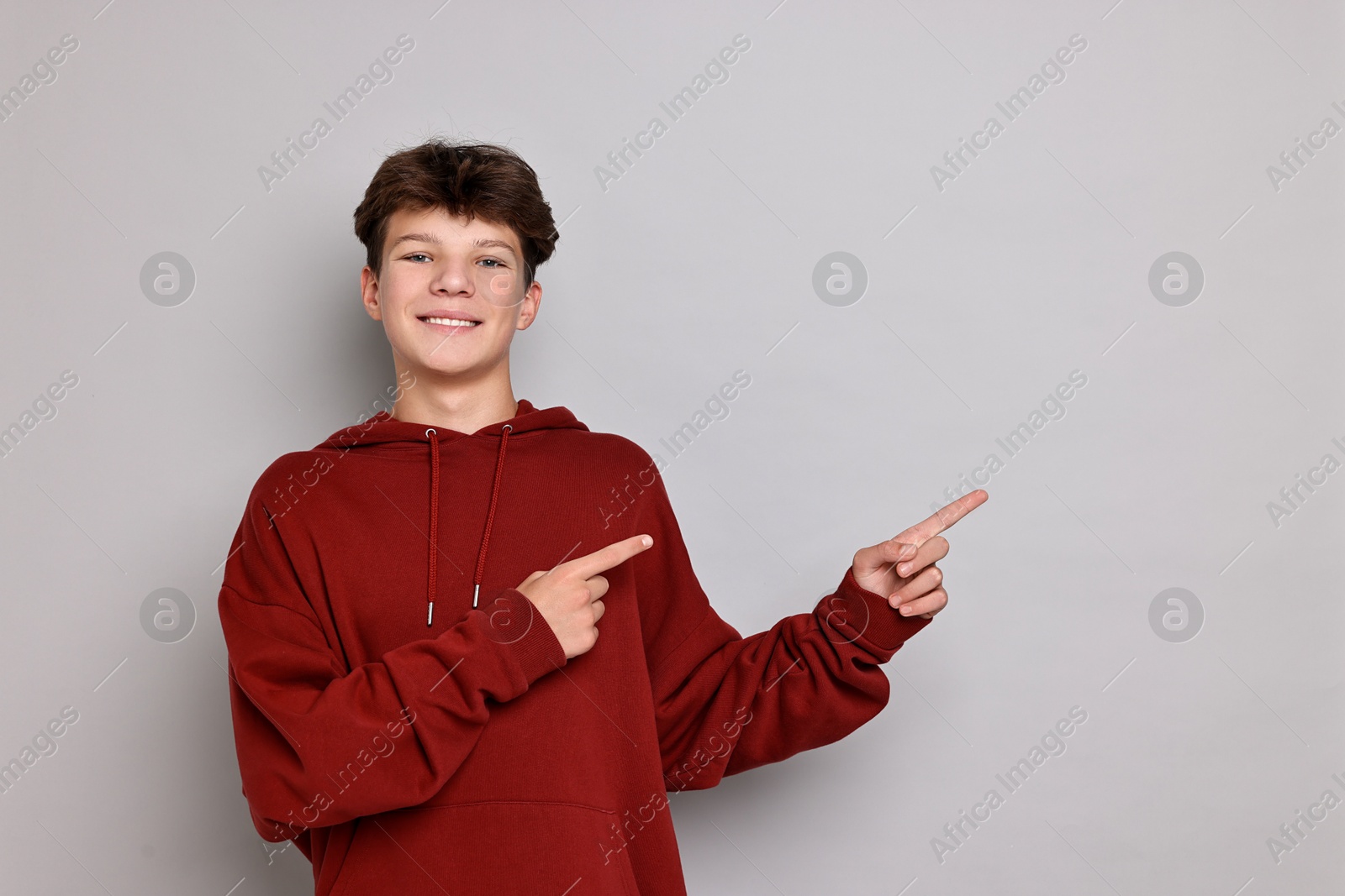 Photo of Portrait of happy teenage boy on light grey background, space for text