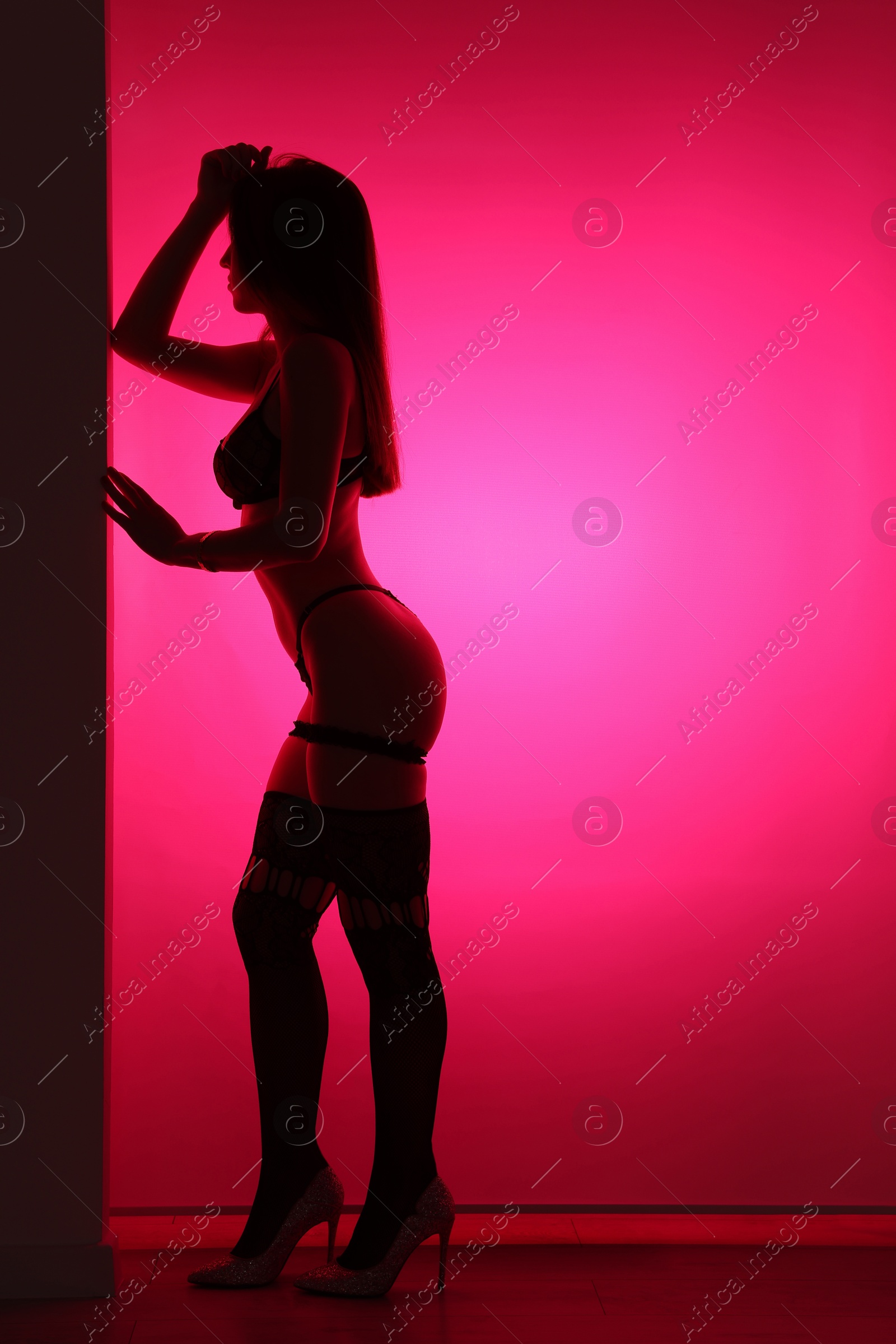 Photo of Prostitution. Woman in underwear indoors in neon lights