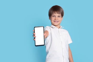 Photo of Cute little boy with smartphone on light blue background